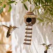 Birdhouse hanging in coconut shell with roof of straw