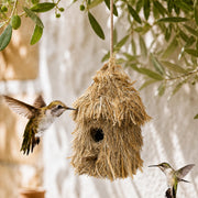 Birdhouse hanging in straw with roof of thatch